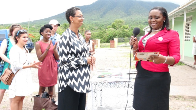 (L-R) University of Virginia Representative Dr Jeanita Richardson presents some books and school supplies to Education Officer and Language Arts Coordinator in the Department of Education on Nevis Avril Elliott on behalf of the Ivor Walters Primary School during a brief ceremony at the school’s compound on May 27, 2014, while students of the University look on